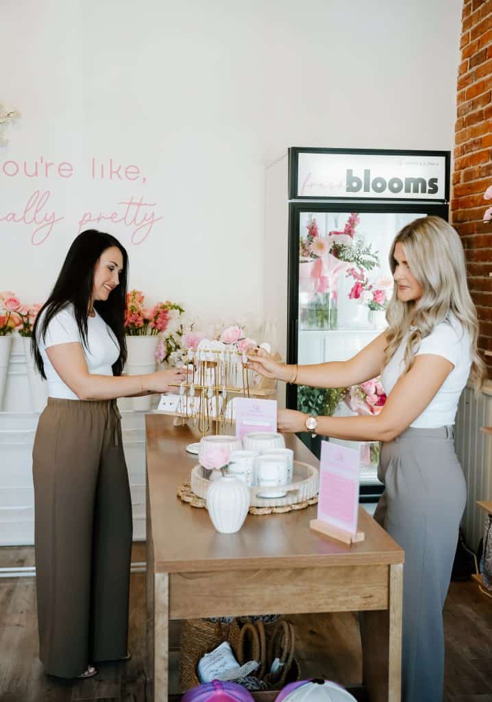 Two women exchanging flowers inside XO Flowers floral shop.