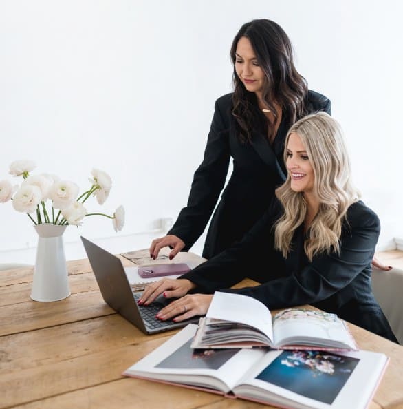 Two women collaborating on event planning with flowers and a laptop.