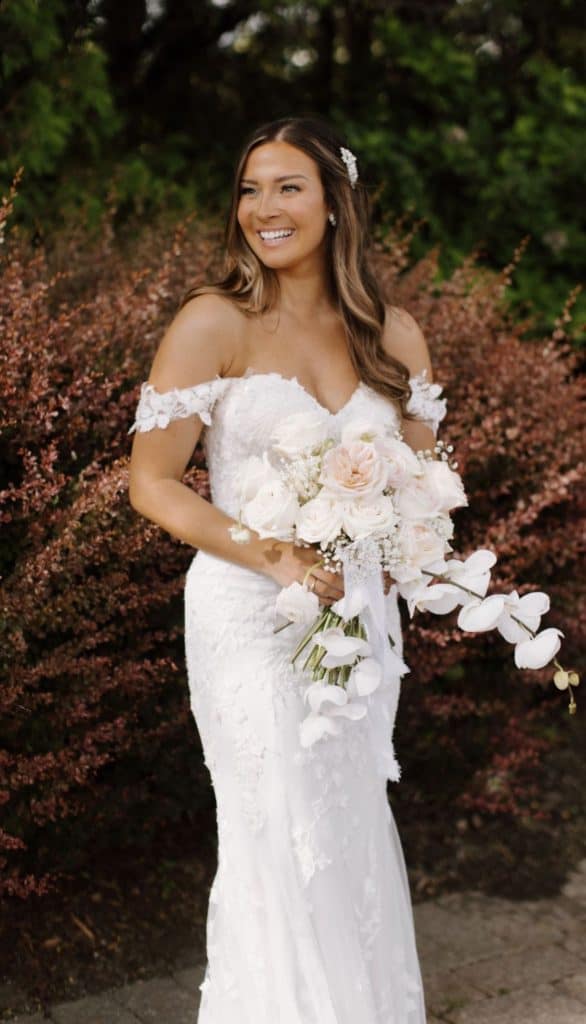 Bride holding a beautiful white floral bouquet outdoors.
