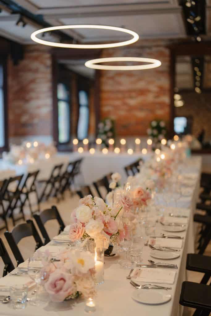 Elegant wedding table with floral centerpieces and modern lighting fixtures.