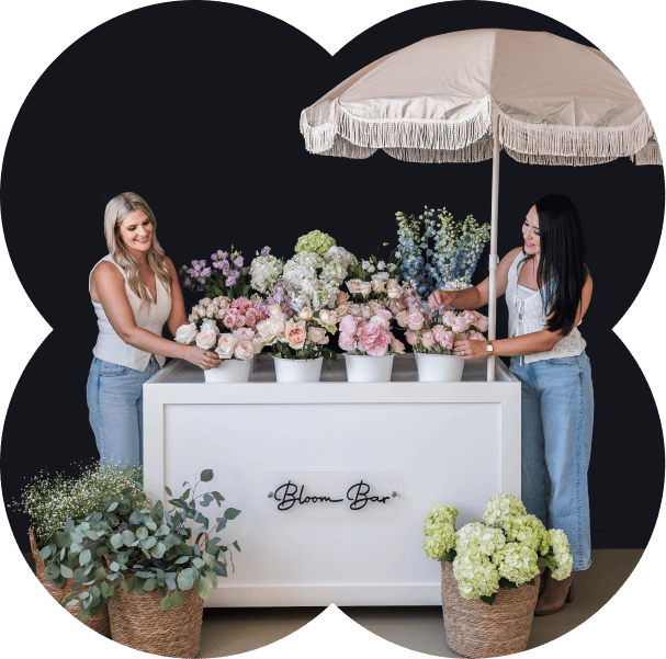 Elegant flower display at XO Flowers Bloom Bar with two women arranging flowers.