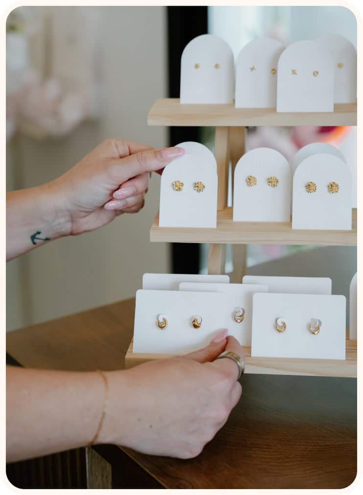 Jewelry display with gold earrings and rings at XO Flowers.