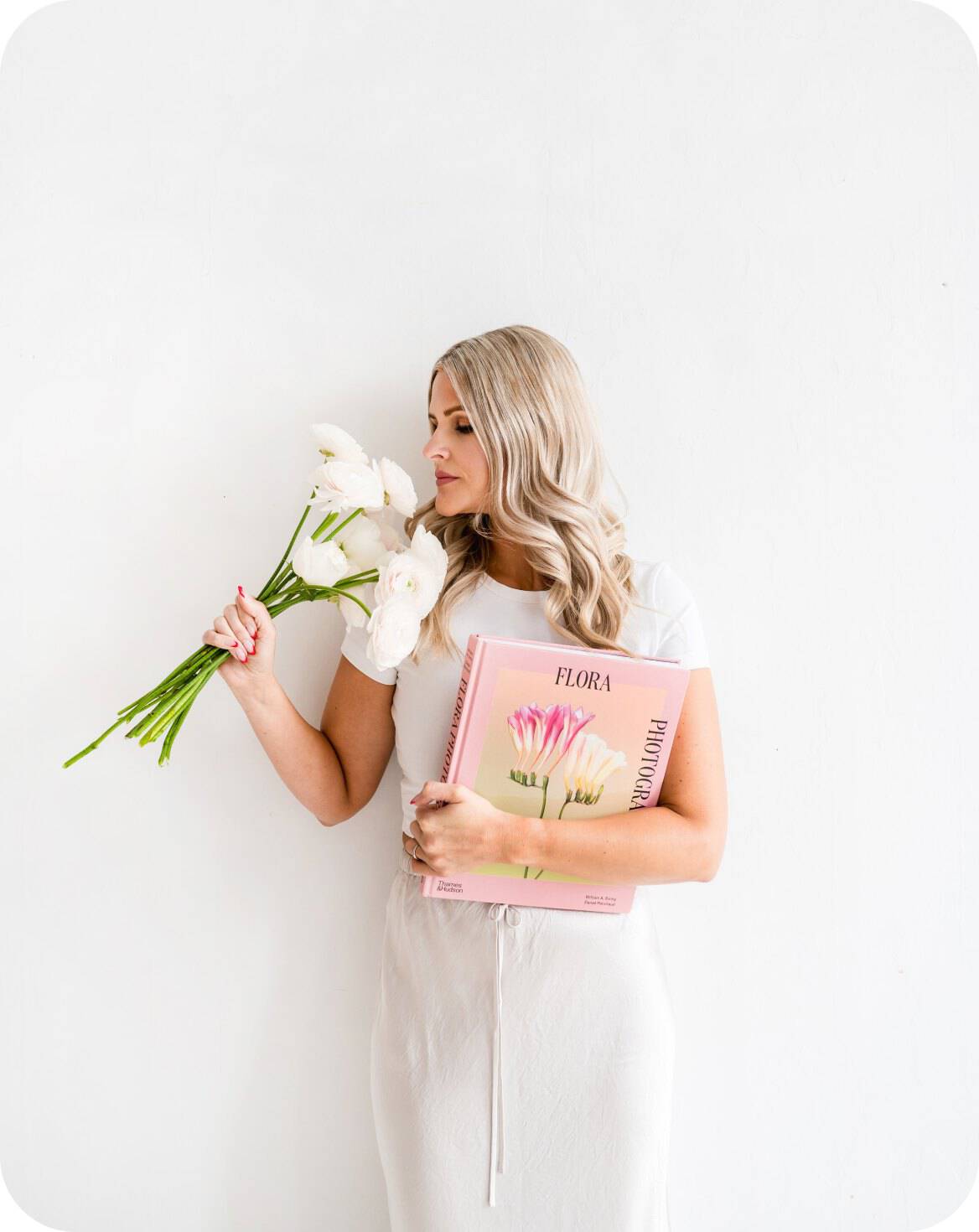 Woman holding white flowers and a pink floral book for elegant event decor.