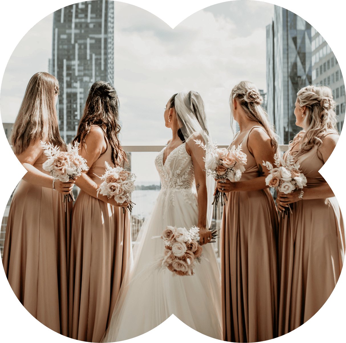 Bride with bridesmaids holding bouquets in urban setting.